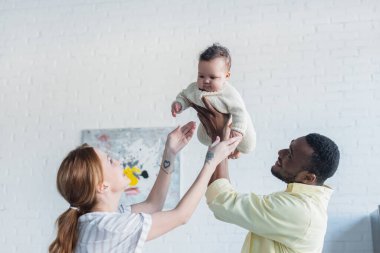 Afro-Amerikalı bir adam evde bir bebek büyütüyor.