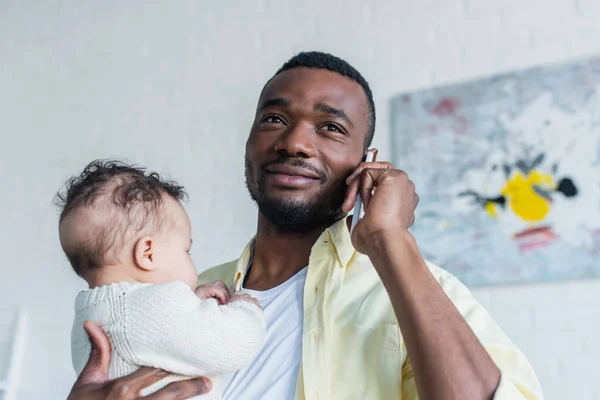 Homem Americano Africano Positivo Segurando Criança Infantil Enquanto Falava Telefone — Fotografia de Stock