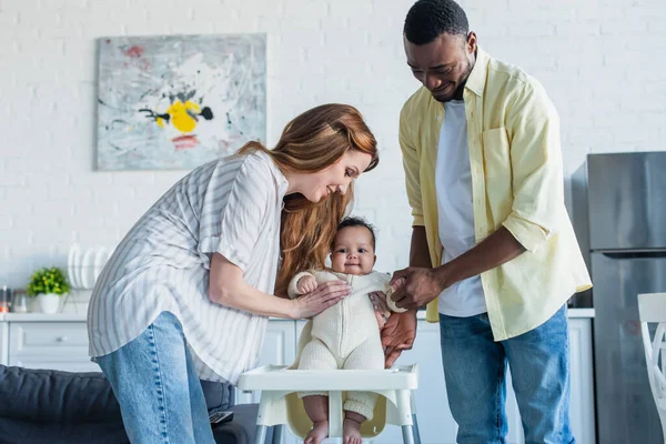 Feliz Pareja Multiétnica Sosteniendo Niño Bebé Cerca Silla Bebé — Foto de Stock