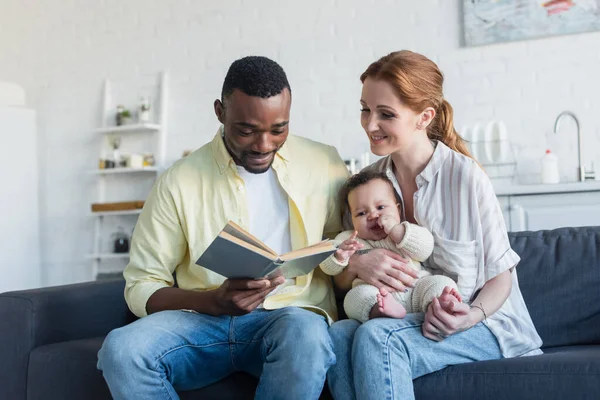 African American Man Reading Book Smiling Wife Infant Daughter — Stock Photo, Image