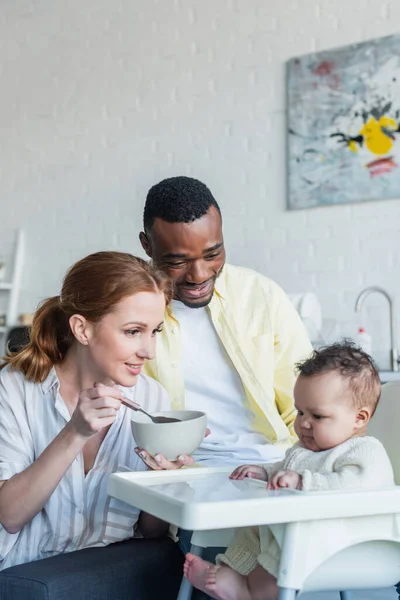 Mulher Feliz Alimentando Criança Infantil Perto Marido Afro Americano — Fotografia de Stock