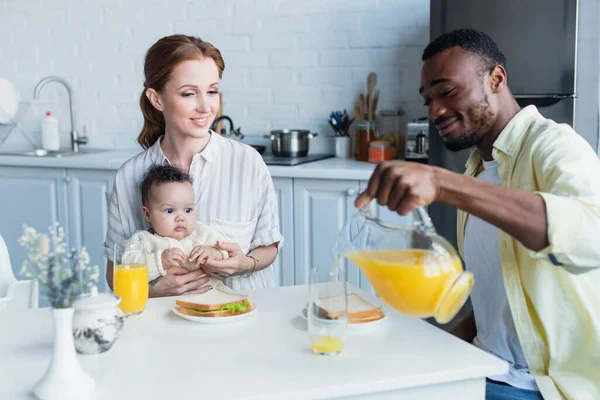 Uomo Africano Americano Versando Succo Arancia Vicino Moglie Figlia Neonata — Foto Stock