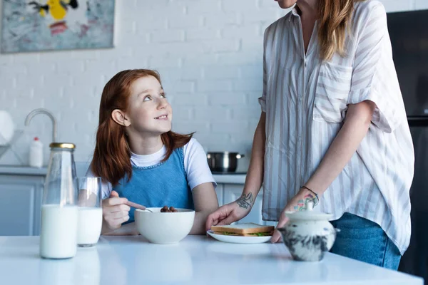 Χαρούμενο Κορίτσι Τρώει Νόστιμα Νιφάδες Καλαμποκιού Κοντά Στη Μητέρα Στην — Φωτογραφία Αρχείου