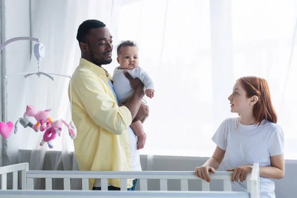 Alegre Africano Americano Hombre Sosteniendo Bebé Chica Cerca Cuna Preadolescente — Foto de Stock