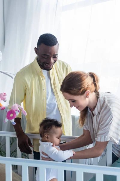 Smiling Woman Holding Infant Daughter Crib African American Husband — Stock Photo, Image