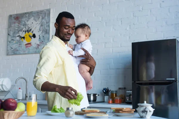 Hombre Afroamericano Feliz Sosteniendo Bebé Niña Mientras Preparan Sándwiches Para — Foto de Stock