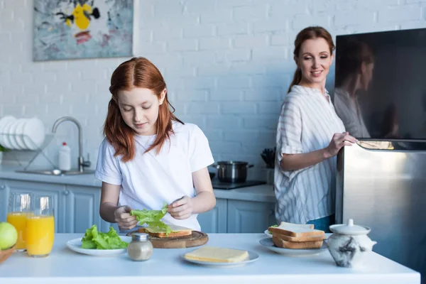 Pleased Woman Looking Daughter Preparing Sandwiches Breakfast — Stock Photo, Image