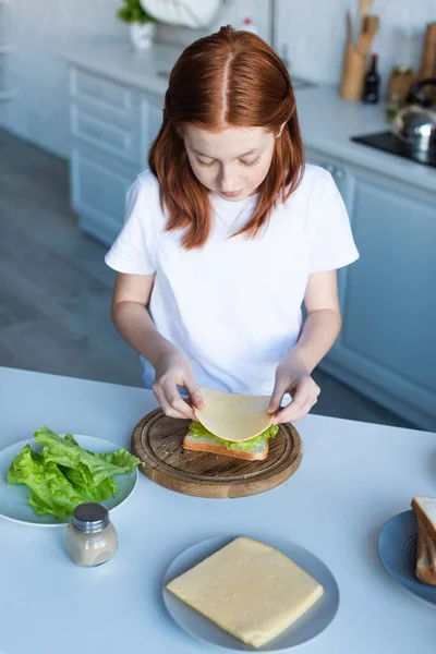 Høy Vinkel Rødhåret Jente Som Tilbereder Sandwich Med Salat Ost – stockfoto