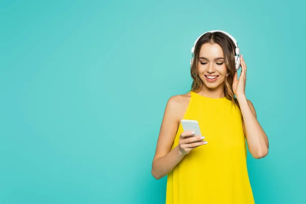 Uśmiechnięta Kobieta Korzystająca Słuchawek Smartfona Odizolowanego Niebiesko — Zdjęcie stockowe