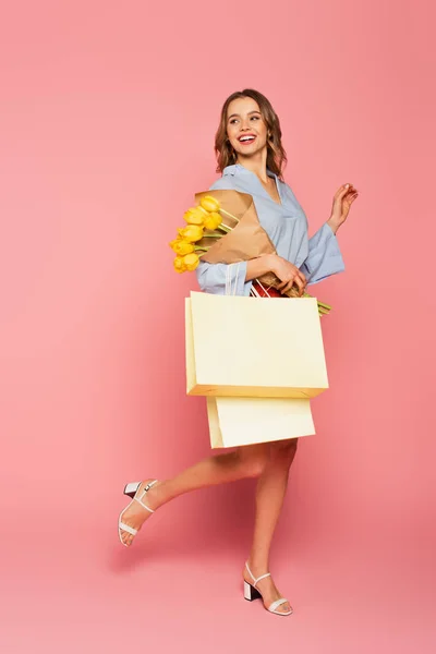 Χαρούμενη Γυναίκα Κρατώντας Μπουκέτο Και Τσάντες Για Ψώνια Ροζ Φόντο — Φωτογραφία Αρχείου