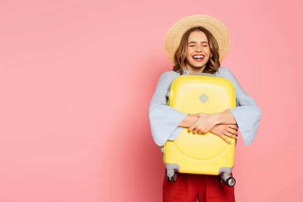 Femme Positive Dans Chapeau Soleil Étreignant Valise Sur Fond Rose — Photo