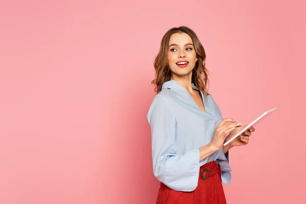 微笑的女人拿着粉红背景的数码平板电脑 — 图库照片