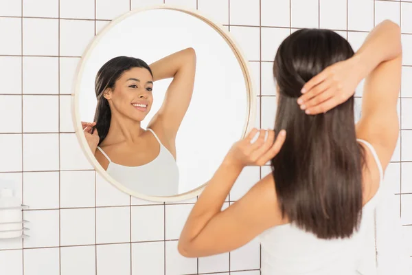 Sonriente Joven Afroamericana Mujer Mirando Espejo Haciendo Peinado Con Las — Foto de Stock