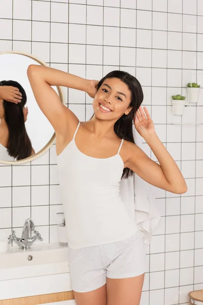 Sonriente Joven Afroamericana Mujer Ropa Blanca Mirando Cámara Haciendo Peinado — Foto de Stock