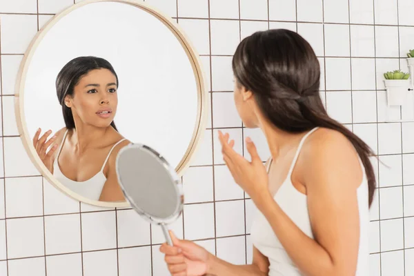 Mujer Afroamericana Joven Estresada Mirando Espejo Sosteniendo Mano Cerca Cara —  Fotos de Stock