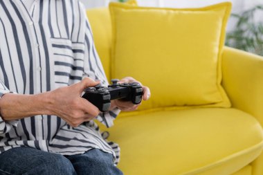 KYIV, UKRAINE - 11 Ocak 2021: Bulanık arkaplanda yaşlı bir kadının elinde kırpılmış joystick görüntüsü 
