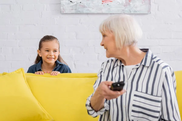 Kind Lächelt Großmutter Mit Fernbedienung Verschwommenen Vordergrund — Stockfoto