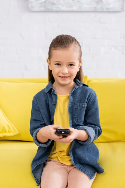 Gadis Tersenyum Dengan Remote Controller Duduk Sofa — Stok Foto