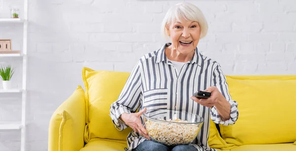 Vrolijke Oudere Vrouw Met Afstandsbediening Popcorn Thuis Banner — Stockfoto