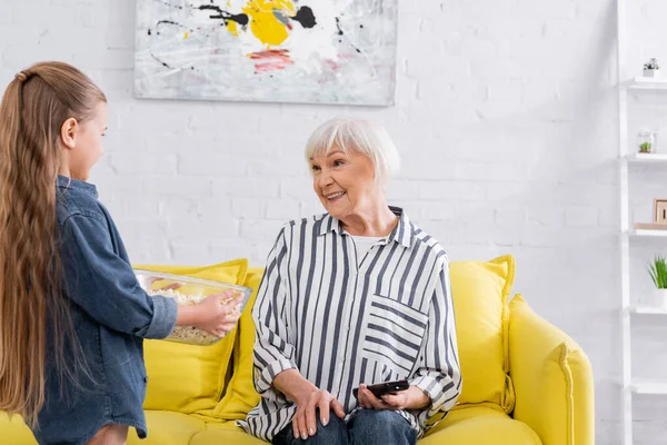 Leende Kvinna Tittar Barn Med Skål Popcorn Hemma — Stockfoto