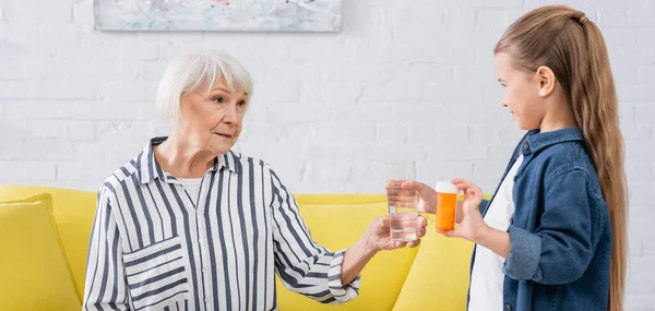 Sonriente Niño Sosteniendo Vaso Agua Pastillas Cerca Abuela Bandera — Foto de Stock