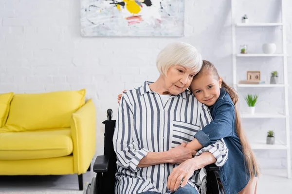 Ragazza Attenta Abbracciando Nonna Sedia Rotelle Casa — Foto Stock