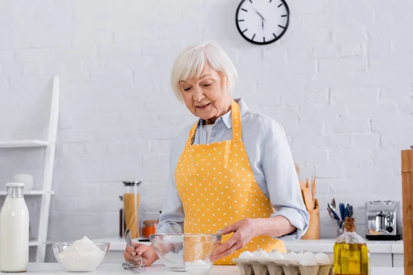 Mulher Sênior Avental Tomando Farinha Perto Leite Ovos Cozinha — Fotografia de Stock