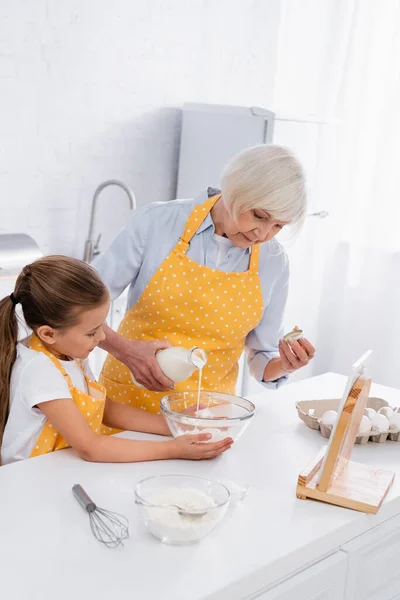 Granny Pouring Milk Kid Ingredients Digital Tablet — Stock Photo, Image