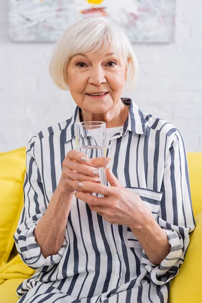 微笑的老妇人看着相机 举着一杯水 — 图库照片