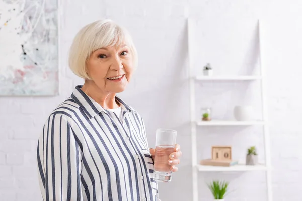Ηλικιωμένη Γυναίκα Ένα Ποτήρι Νερό Χαμογελώντας Στην Κάμερα Στο Σπίτι — Φωτογραφία Αρχείου