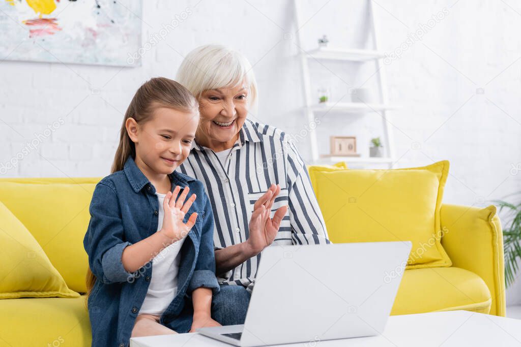 Smiling grandmother and child having video call on laptop at home 