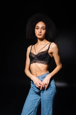 Siyah arka planda kameraya bakan seksi Afrikalı Amerikalı kadın. 