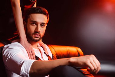 Kırmızı ışıklandırmalı siyah arka planda zarif erkek arkadaşına dokunan bir kadın.