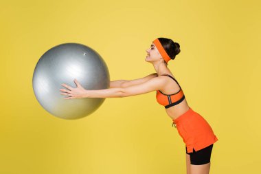 Gülümseyen sporcunun yan görünüşü. Spor yaparken spor topu sarı renkte izole edilmiş.