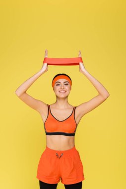 Sarı bantlı, turuncu spor giyim eğitimli neşeli bir kadın.