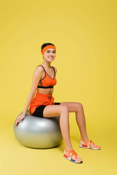 Vrolijke Sportvrouw Zittend Zilver Grijze Fitness Bal Gele Achtergrond — Stockfoto