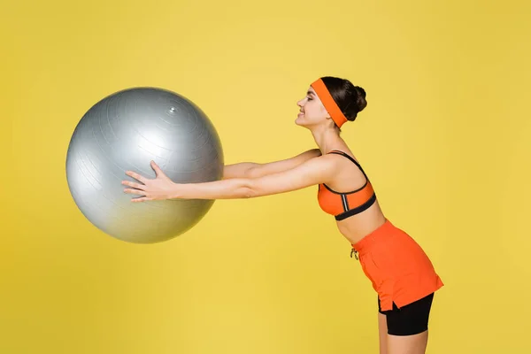 Side View Smiling Sportswoman Exercising Fitness Ball Isolated Yellow — Foto de Stock