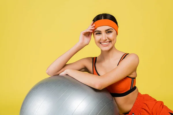 Potěšená Sportovkyně Při Pohledu Kameru Blízkosti Fitness Míč Izolované Žluté — Stock fotografie