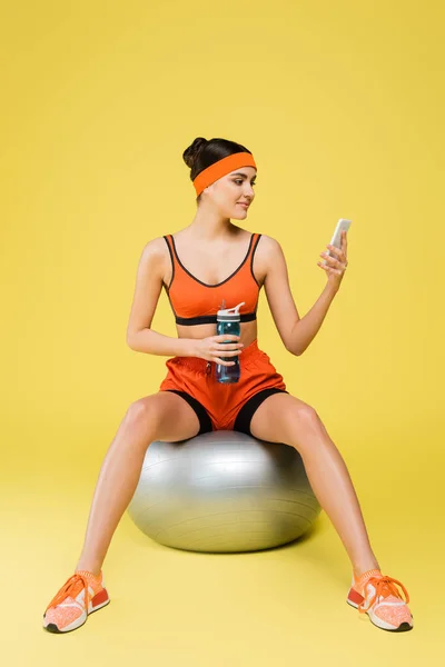 Woman Sportswear Sitting Fitness Ball Sports Bottle Looking Smartphone Yellow — 스톡 사진