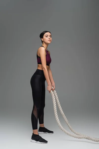 Young Sportswoman Looking Camera While Standing Battle Ropes Grey Background — Stock Photo, Image