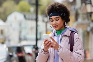 Kentsel caddede akıllı telefon kullanan Afrikalı Amerikalı kadın. 