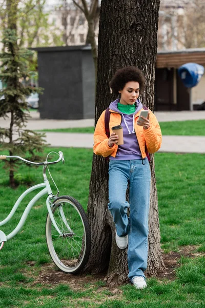 Africano Americano Mulher Com Café Para Smartphone Perto Árvore Bicicleta — Fotografia de Stock