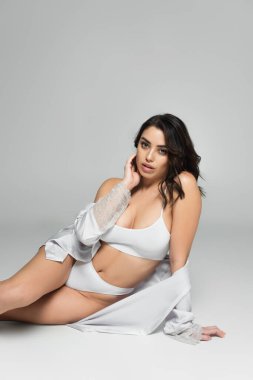 İç çamaşırlı esmer model ve gri arka planda ipek bornoz. 