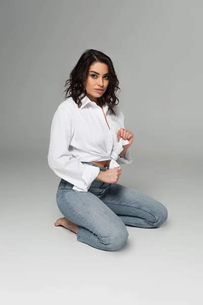 Mujer Seductora Atando Camisa Blanca Sobre Fondo Gris — Foto de Stock