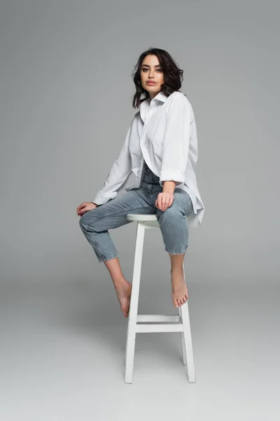 Hübsche Frau Jeans Und Hemd Auf Stuhl Vor Grauem Hintergrund — Stockfoto