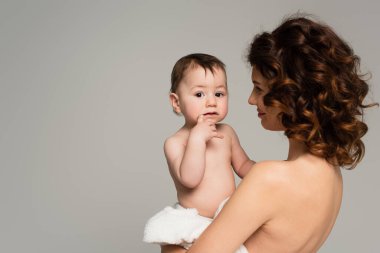 Neşeli anne kucağında küçük oğlu Gri yolda yalnız başına. 