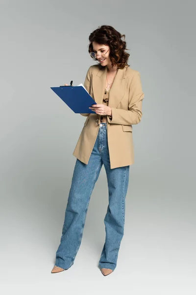 Full Length Happy Businesswoman Glasses Blazer Holding Clipboard Grey — Stock Photo, Image