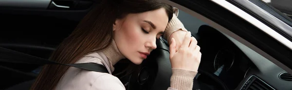 年轻疲惫的女人坐在汽车和横幅上睡觉 — 图库照片