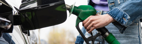 cropped view of woman with petrol pistol near car on gas station, banner
