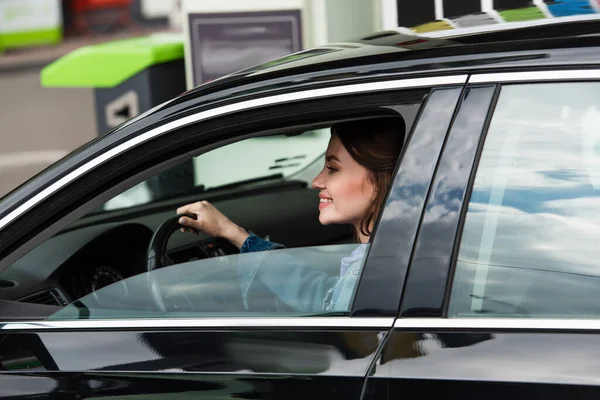 若い女性が車を運転しながら笑顔で — ストック写真